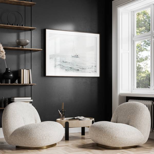 Modern living room with two beige armchairs, a coffee table, and a dark wall with a framed picture.