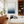 Modern living room with a white sofa, wooden bookshelf, and framed artwork of a blue ocean.